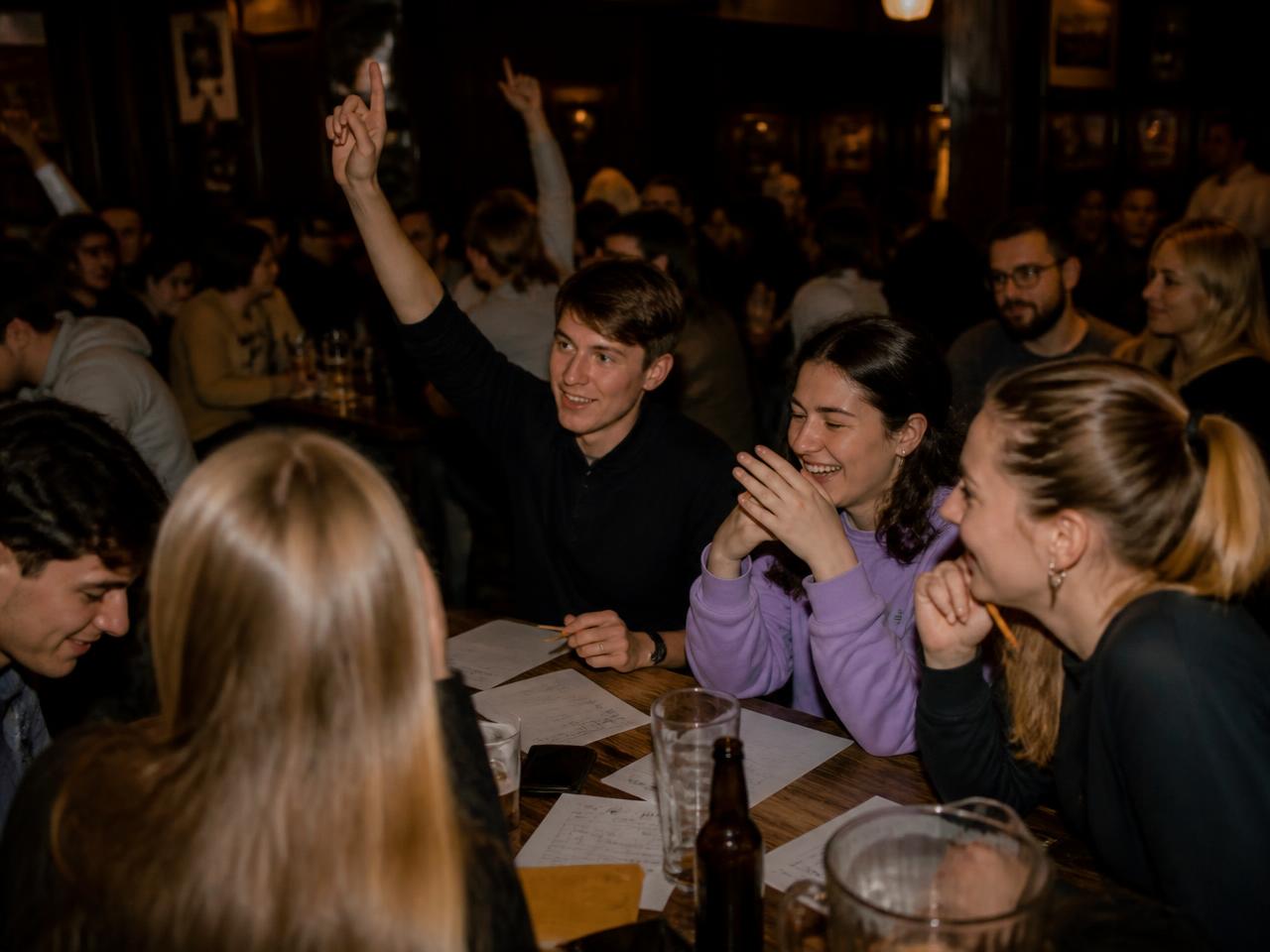 Quiz night at a bar: students at a wooden table with answer sheets